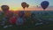 Aerial view of a morning launch of hot air balloons at a hot air balloon festival at sunrise on a sunny summer day