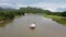 Aerial view of motor boat pulling raft house in river with mountain and sky view. landscape of floating hotel on river in Kanchana