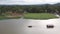 Aerial view of motor boat pulling raft house in river with mountain and sky view. landscape of floating hotel on river in Kanchana