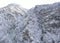 Aerial view of mountain with boundary tower, forest underneath fog, slopes with snow covered in Switzerland, cloudy