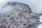 Aerial view of mountain with boundary tower, forest underneath fog, slopes with snow covered in Switzerland, cloudy