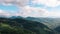 Aerial view of mountain gorge hills covered by green forest. Drone camera pan and flies over mountain settlement