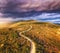 Aerial view of mountain road, green forest, dramatic overcast sky