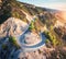 Aerial view of mountain road, green forest at sunset in summer