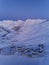 Aerial view of mountain village chalets illuminated with night street lights along switchbacks curvy road at twilight on