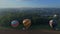 Aerial view of multiple hot air balloons landing during a festival in a Amish farm