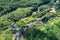 Aerial view, multiple waterfalls on Big Island of Hawaii; pools below the drops. Surrounded by green foliage of rainforest.