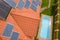 Aerial view of a new autonomous house with solar panels and water heating radiators on the roof and green yard with blue swimming