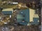 Aerial view of new residential house cottage and garage or barn with shingle roof on fenced yard on sunny day