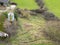 Aerial view of a now derelict dairy farm showing the large metallic grain hopper and some barn sheds.