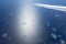 Aerial view of ocean through a plane window. Wing of airplane with blue sky and beauty clouds over the ocean. Aerial sea view