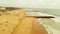 Aerial view of ocean with rocky piers and sandy beach with unrecognisable people. Costa Da Caparica