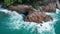 Aerial view of ocean`s beautiful waves and rocky tropical coast with Thai flag on the rock`s peak