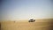 Aerial view on Off-road adventure with SUV in Arabian Desert at sunset with Dubai skyline or cityscape. Desert touring