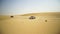 Aerial view on Off-road adventure with SUV in Arabian Desert at sunset with Dubai skyline or cityscape. Desert touring