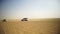 Aerial view on Off-road adventure with SUV in Arabian Desert at sunset with Dubai skyline or cityscape. Desert touring
