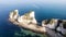 An aerial view of the Old Harry Rocks with crystal clear water, white cliffs and speed boat in the background under a hazy sky