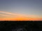 Aerial view of orange sunrise over the silhouette of lush green woods