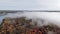 Aerial view over a bright autumn forest in dense fog on the banks of a calm river