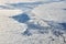 Aerial view over clouds top to snow covered rivers, fields and roads, winter fresh frosty air