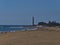 Aerial view over crowded beach Playa de Maspalomas with sand dune in front and lighthouse Faro de Maspalomas, Gran Canaria, Spain.