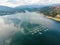 Aerial view over a fish farm with lots of fish enclosures on cages