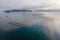 Aerial view over a fish farm with lots of fish enclosures on cages