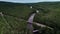 Aerial view over forest river with bridges and parked vehicle along an empty road in northern Europe