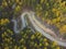 Aerial view over mountain road inside forest during sunrise