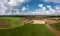 Aerial view over a ranch with horses and a village in the background under a blue, wonderful fluffy clouded sky.