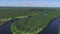 Aerial view over river and green valley near countryside houses. Shot. Beautiful narrow river curving through fields