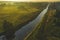 Aerial view over a valley with mist at sunrise. Drone flying over summer river, meadow and forest. The rays of the sun make their