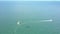 Aerial view parachute flies behind white motorboat over sea