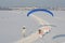 Aerial view of a paramotor flying over a snowy road with speed limit sign