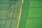 Aerial view of a path between two arable land with a car in the middle, taken at an abstract angle from a height of 100 metres