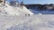 Aerial view of people walking across a snow covered area in the sun . Mountain shadow covering part of area. Mountain