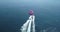 Aerial view of person parasailing and motorboat
