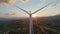 Aerial view of a person on a wind turbine at sunset with rolling hills.