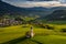 Aerial view of picturesque valley with chapel in Bolzano at sunset, Trentino, amazing green meadows of the mountains of Italy,