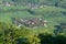 An aerial view of a picturesque village with quaint houses, lush rice fields, and verdant trees.