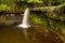 Aerial view of a picturesque waterfall and pool in a narrow canyon and green forest Sgwd Gwladys, Brecon Beacons, Wales