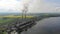 Aerial view Pipe teleplastic that emit black smoke, on the background of beautiful nature, green fields and a large lake