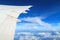 Aerial view of plane window above clouds under blue sky. View from aircraft window