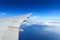 Aerial view of plane window above clouds under blue sky. View from aircraft window
