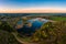 Aerial view of a pond surrounded by forest at sunset