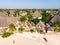 Aerial view of pool, umbrellas, sandy beach with green Palm trees. Coast of Indian ocean at sunset in summer. Zanzibar