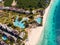 Aerial view of pool, umbrellas, sandy beach with green Palm trees. Coast of Indian ocean at sunset in summer. Zanzibar