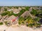 Aerial view of pool, umbrellas, sandy beach with green Palm trees. Coast of Indian ocean at sunset in summer. Zanzibar