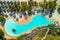 Aerial view of pool, umbrellas, sandy beach with green trees