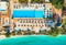 Aerial view of pool, umbrellas, sandy beach with green trees, sea